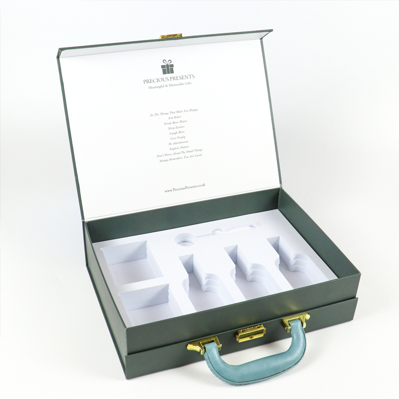 Open green rigid box featuring a white paperboard insert with precisely shaped cavities, designed for secure storage and transport of multiple jewelry pieces.