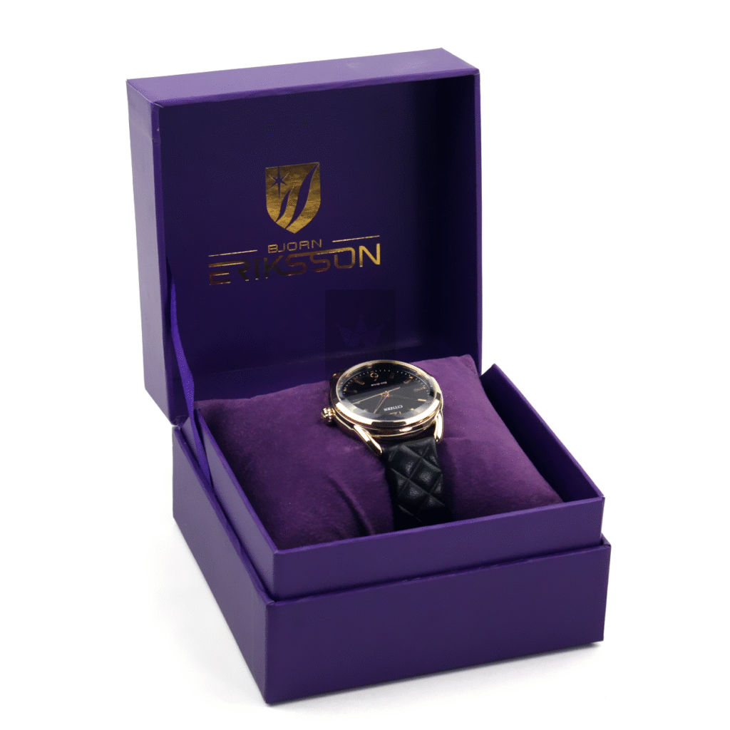 Deep purple rigid watch box with gold foil logo and matching velvet lining, showcasing a black dial watch—designed for high-end or limited-edition timepieces.