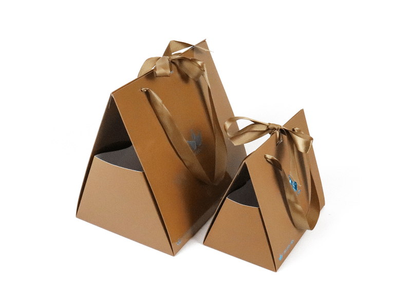 Custom brown pyramid-shaped paper gift boxes with satin ribbon handles and bow closures, designed for luxury gifts, cosmetics, jewelry and premium retail packaging.
