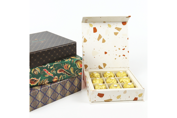 Custom printed chocolate gift packaging boxes with decorative patterns and a compartment divider holding individually wrapped chocolates.