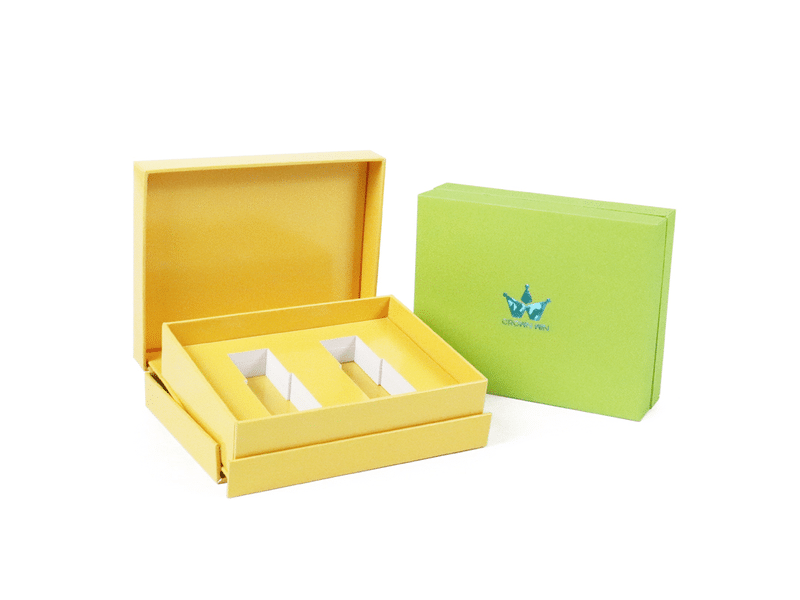 Custom yellow hinged rigid gift box with two precision die-cut compartments and matching green presentation box, designed for cosmetics, skincare and premium product packaging.