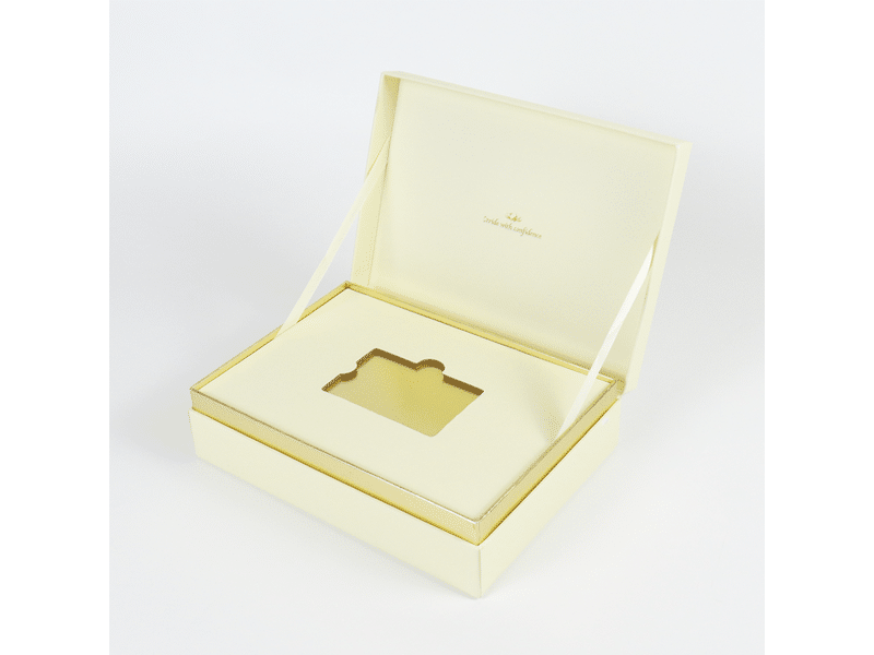 Custom ivory hinged-lid rigid gift box with ribbon lid supports, gold trim and a precision die-cut insert for luxury jewelry, cosmetics and premium product packaging.