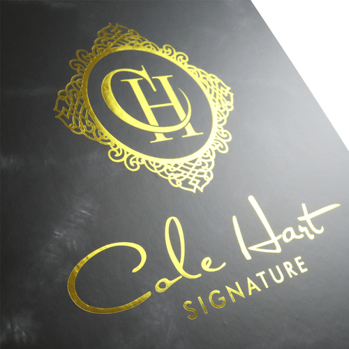 High-end custom-printed matte black cardboard packaging box featuring a shiny hot-stamped gold foil signature logo and intricate vintage crest emblem.