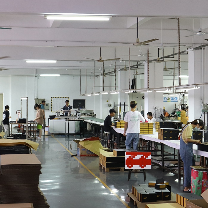 Inside the custom packaging box manufacturing facility, showing professional workers on the active assembly line hand-crafting luxury rigid magnetic gift boxes with strict quality control.