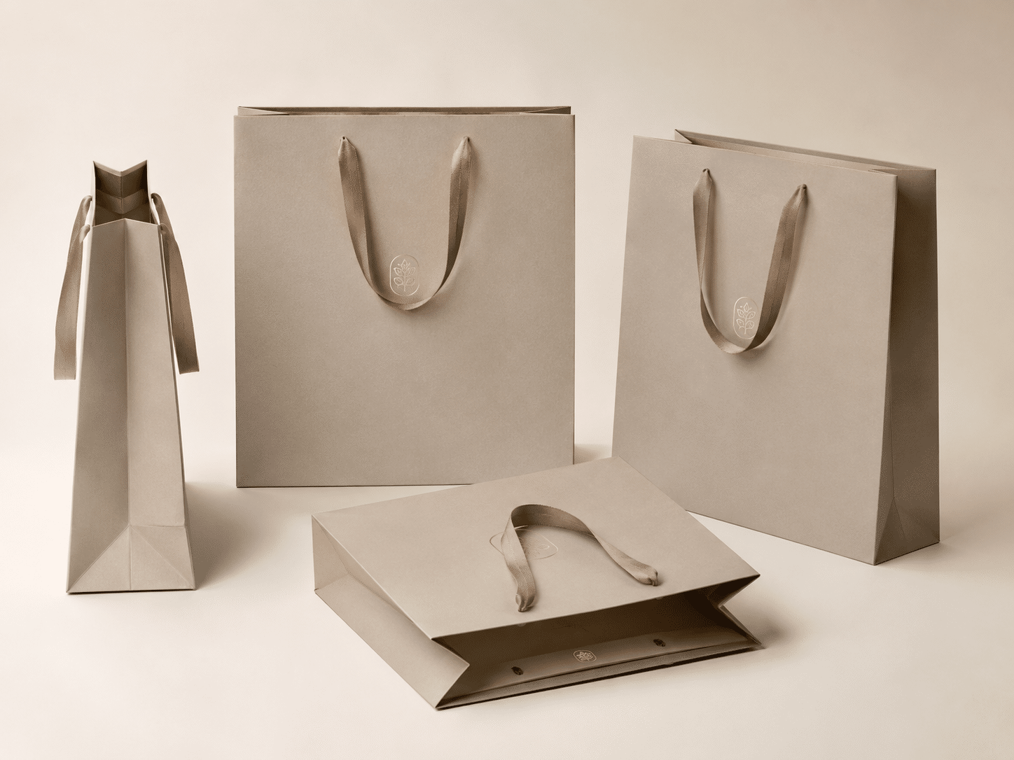 Custom beige paper shopping bags shown from front, side and open views with soft ribbon handles for luxury retail packaging