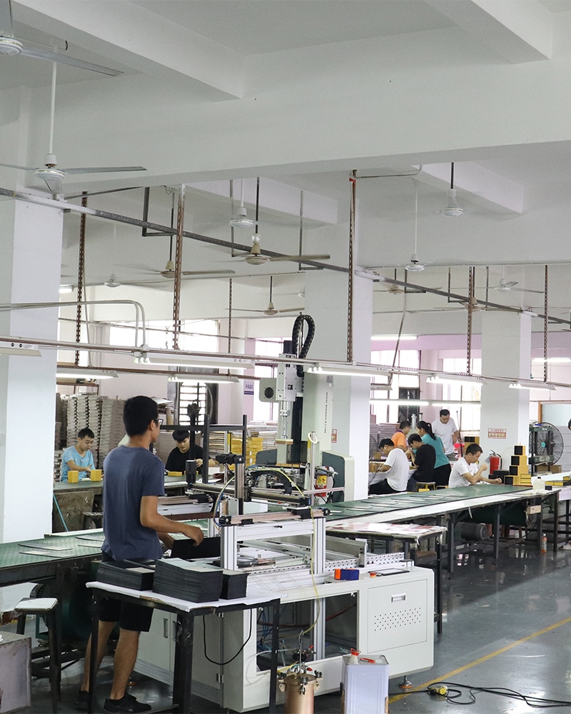 Custom kraft packaging box manufacturing factory with workers operating assembly equipment and producing paper boxes for bulk orders