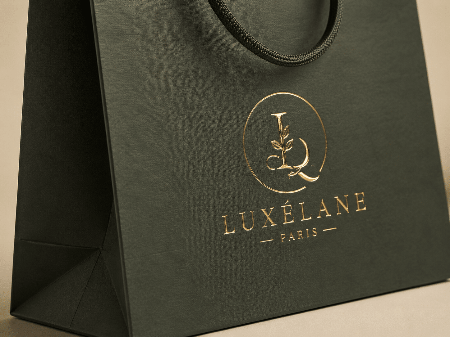 Close-up of a custom dark green textured paper bag with braided rope handles and metallic gold foil stamped logo