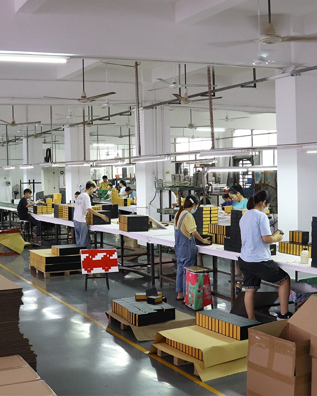 Workers assembling and inspecting custom corrugated mailer boxes in a professional packaging factory production workshop