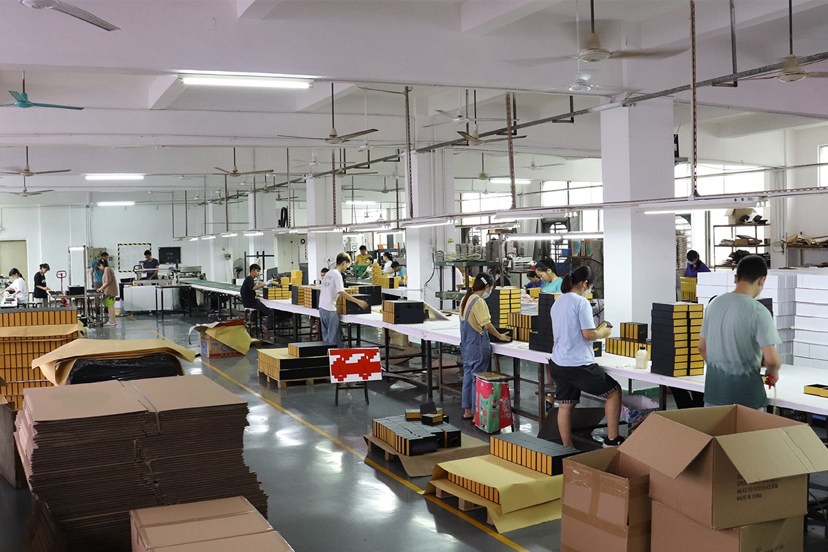 Custom rigid box factory workshop with workers assembling, finishing, inspecting and packing luxury paper packaging boxes on the production line.