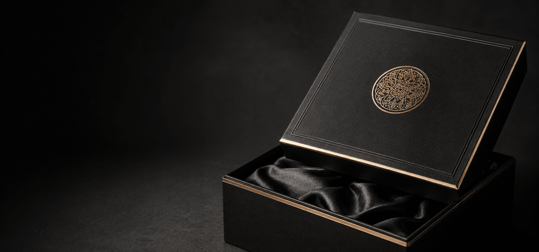 Luxury black rigid presentation box with gold foil emblem, gold edge detailing and soft black satin lining for premium product packaging