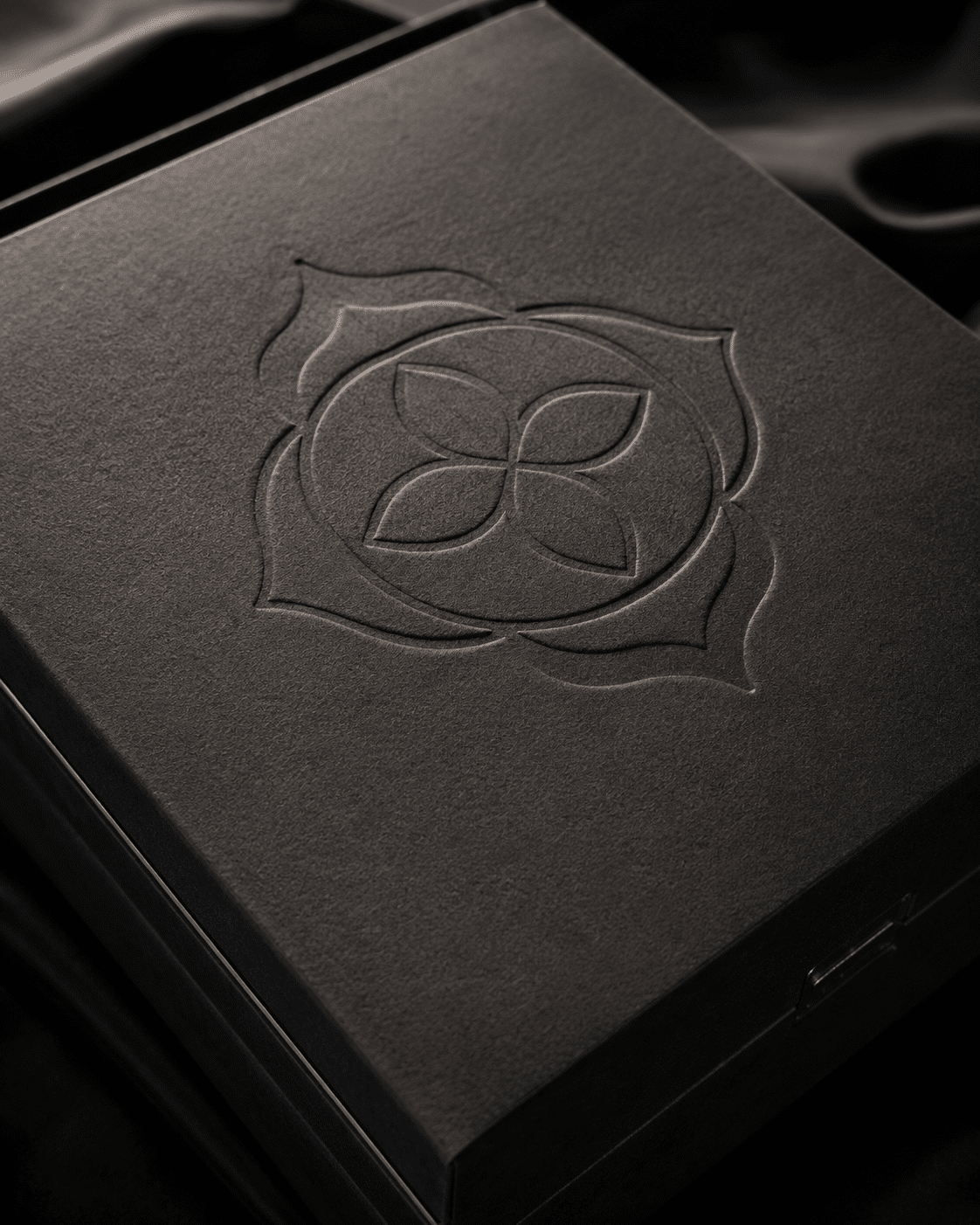 Close-up of a black textured rigid box featuring a subtle blind embossed logo for minimalist luxury packaging