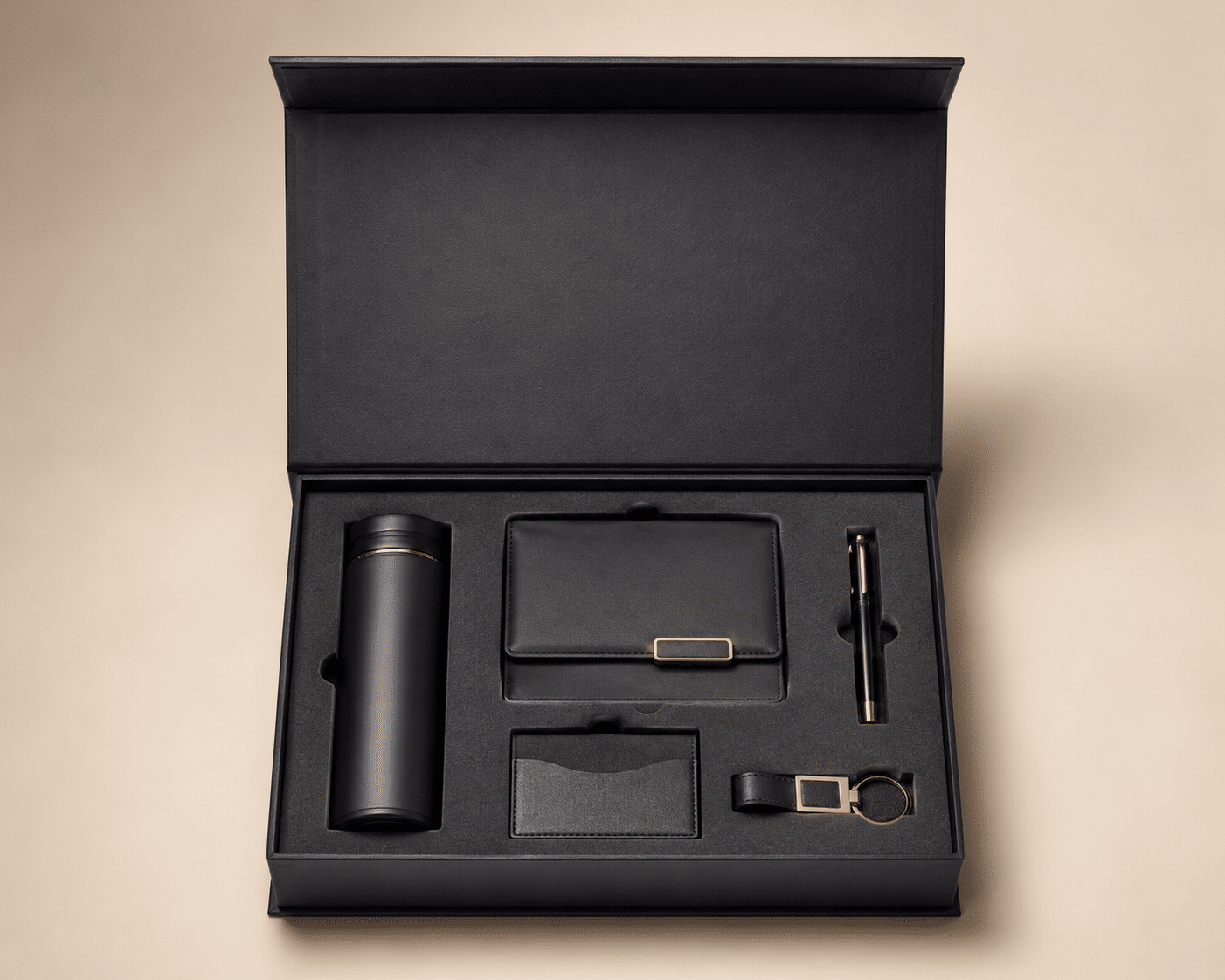 Open black magnetic corporate gift box with a custom EVA foam insert holding a bottle, wallet, pen, card holder and keychain.