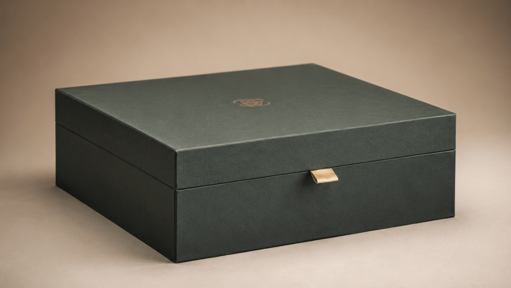 Closed dark green luxury rigid gift box with a gold logo and ribbon pull tab for premium product packaging.