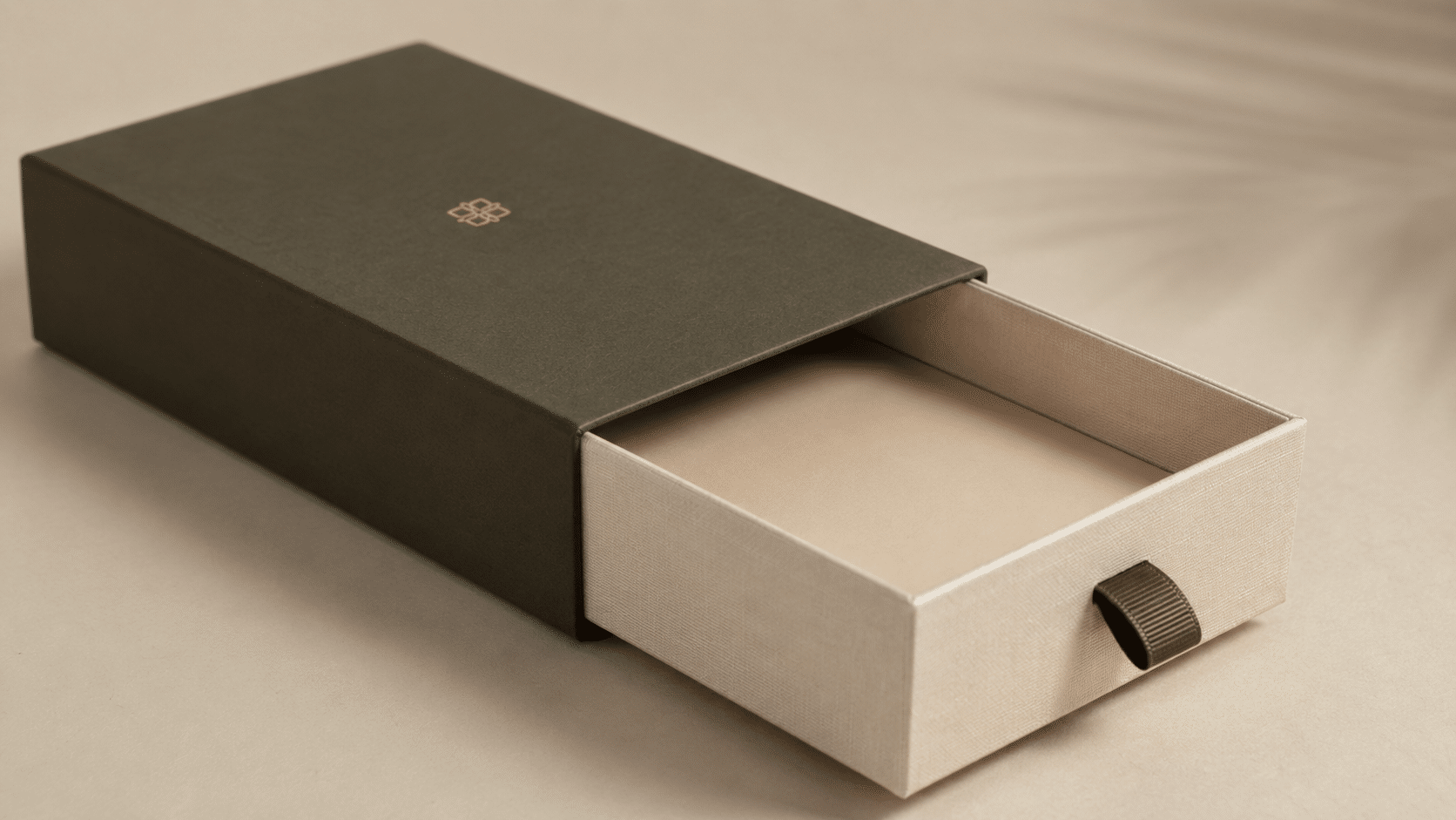 Dark green and cream custom drawer packaging box featuring a ribbon pull handle and gold foil logo.