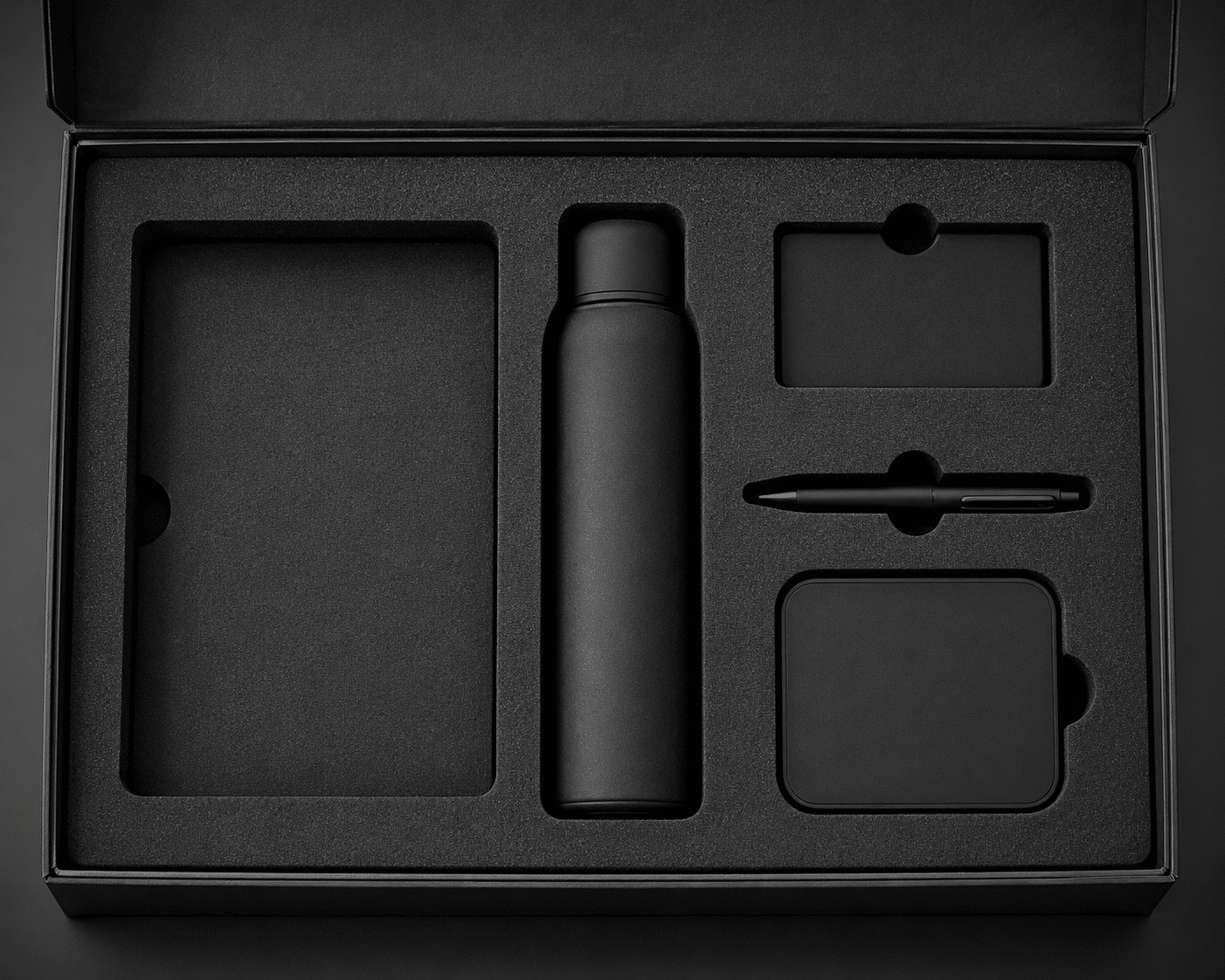 Black precision-cut EVA foam insert designed to secure a bottle, notebook, pen and accessories inside a rigid gift box.