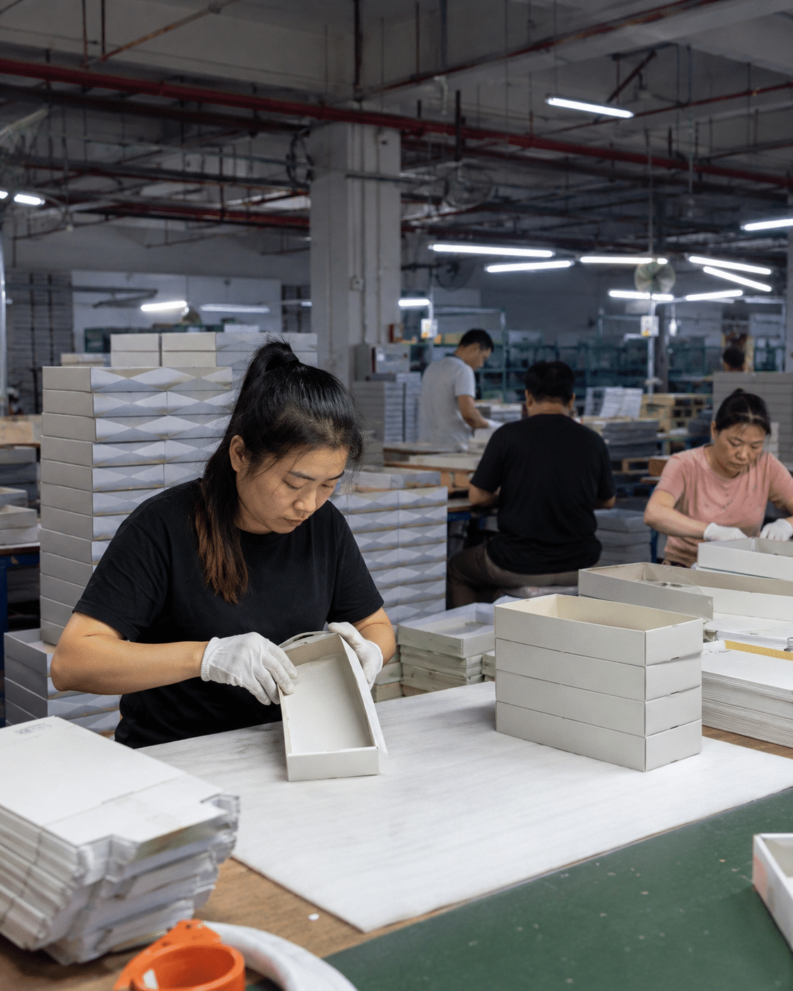 Packaging factory worker assembling and inspecting custom rigid paper boxes during the production and quality-control process.