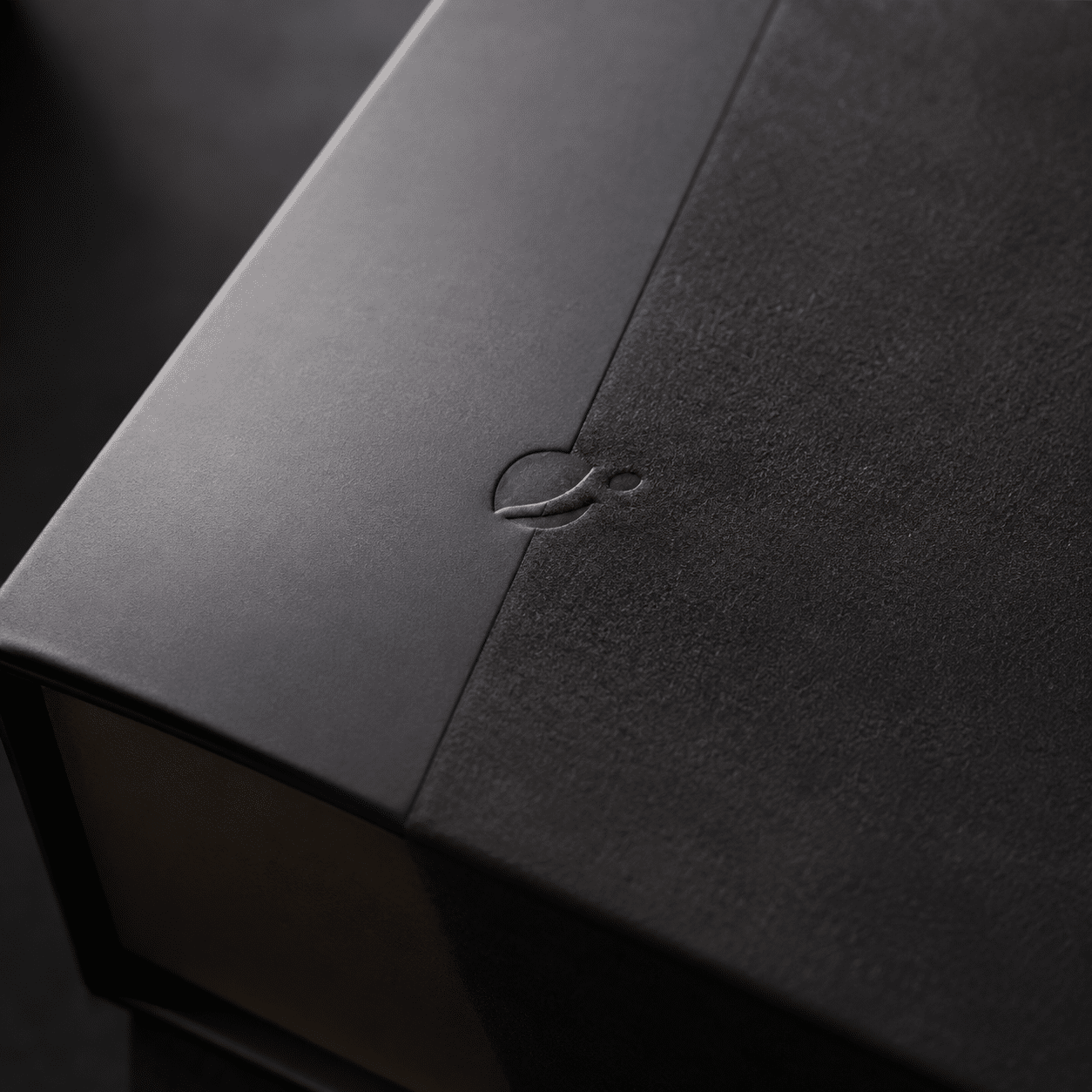 Close-up of a precision die-cut opening tab and textured paper surface on a custom black rigid box.