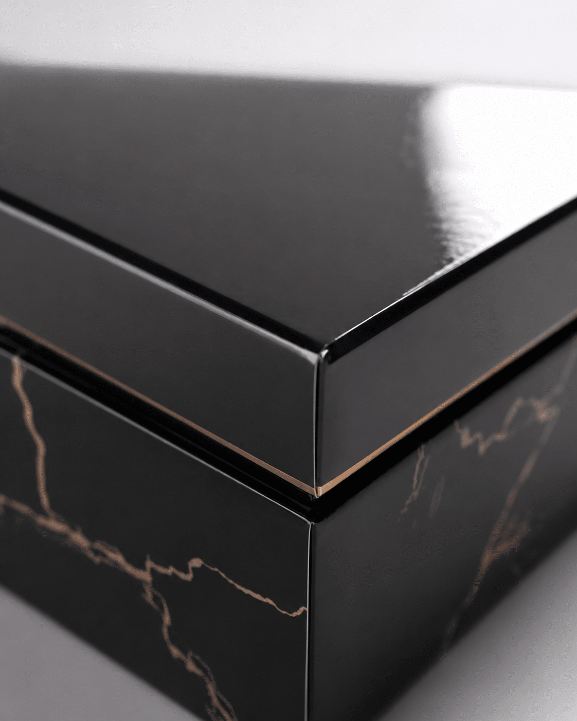Close-up of a glossy black rigid box with reflective lamination, polished edges and decorative marble-style lower panels