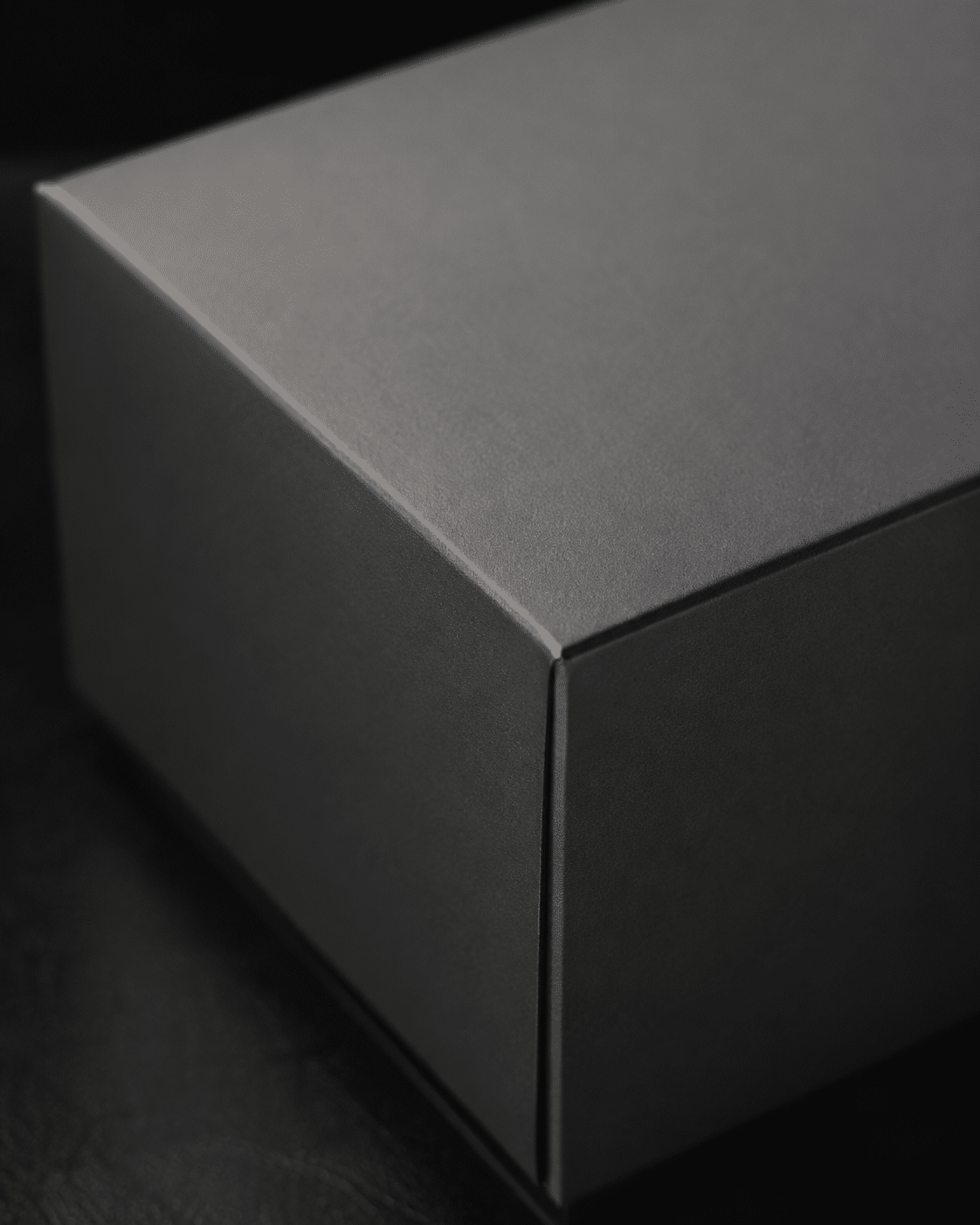 Close-up of a minimalist black rigid box with smooth matte lamination, clean wrapped corners and a refined soft-touch appearance
