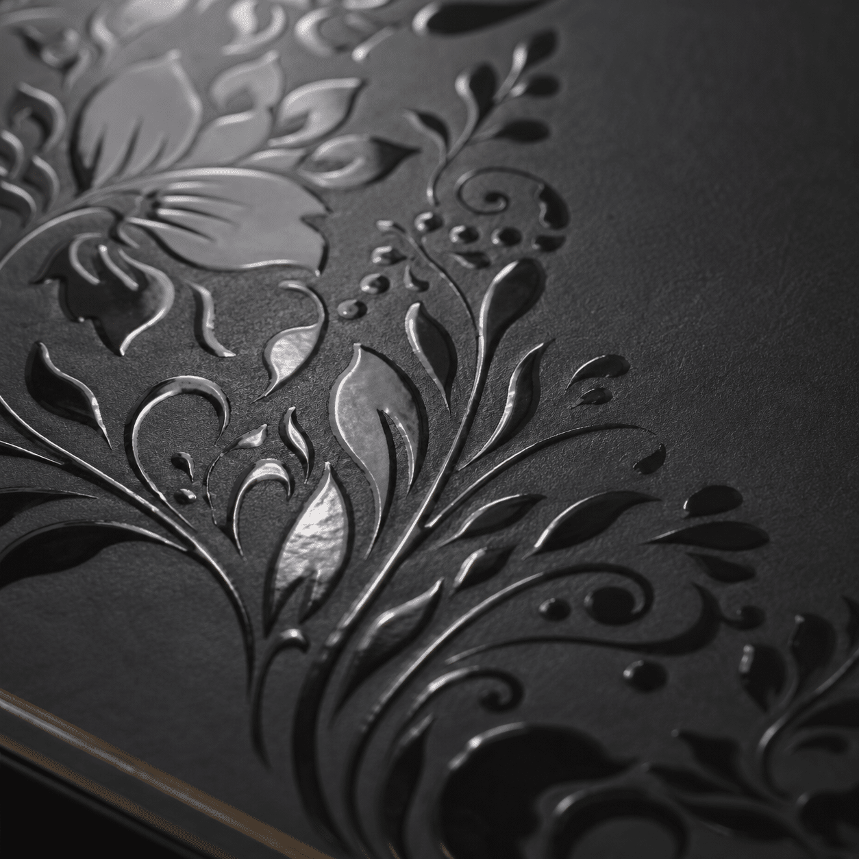 Close-up of glossy black spot UV floral artwork applied to a matte black custom rigid packaging box.
