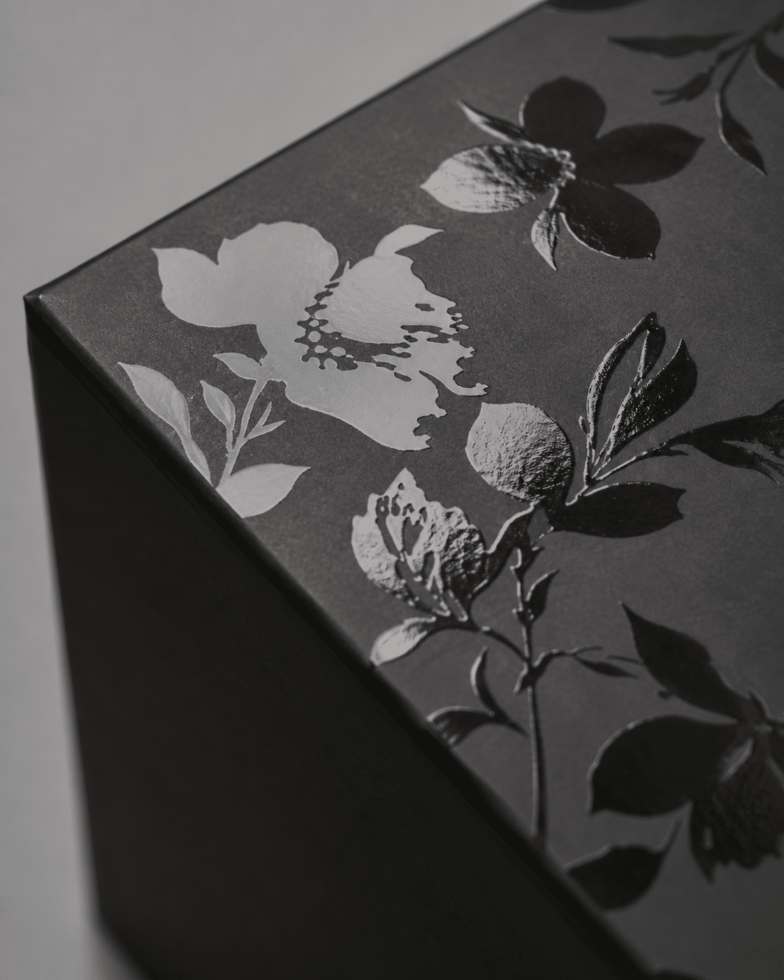 Matte black custom packaging box with glossy spot UV floral artwork creating a premium tone-on-tone finish