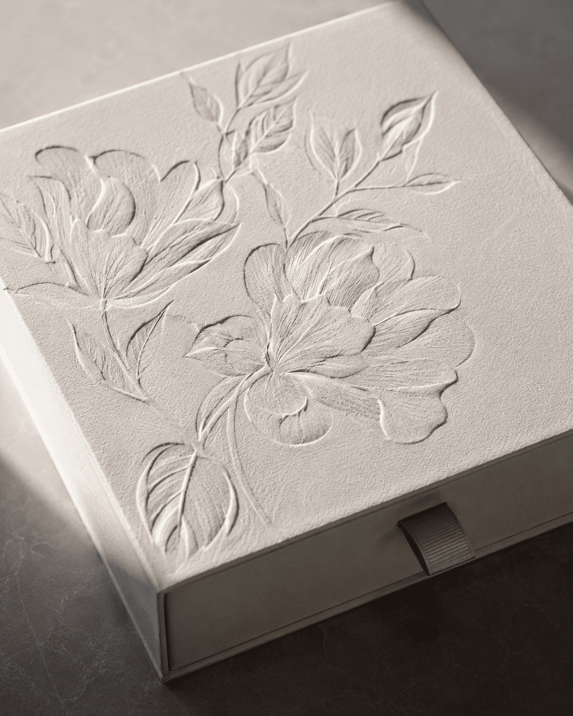 Custom white rigid drawer gift box with raised floral embossing, textured paper and a matching ribbon pull tab